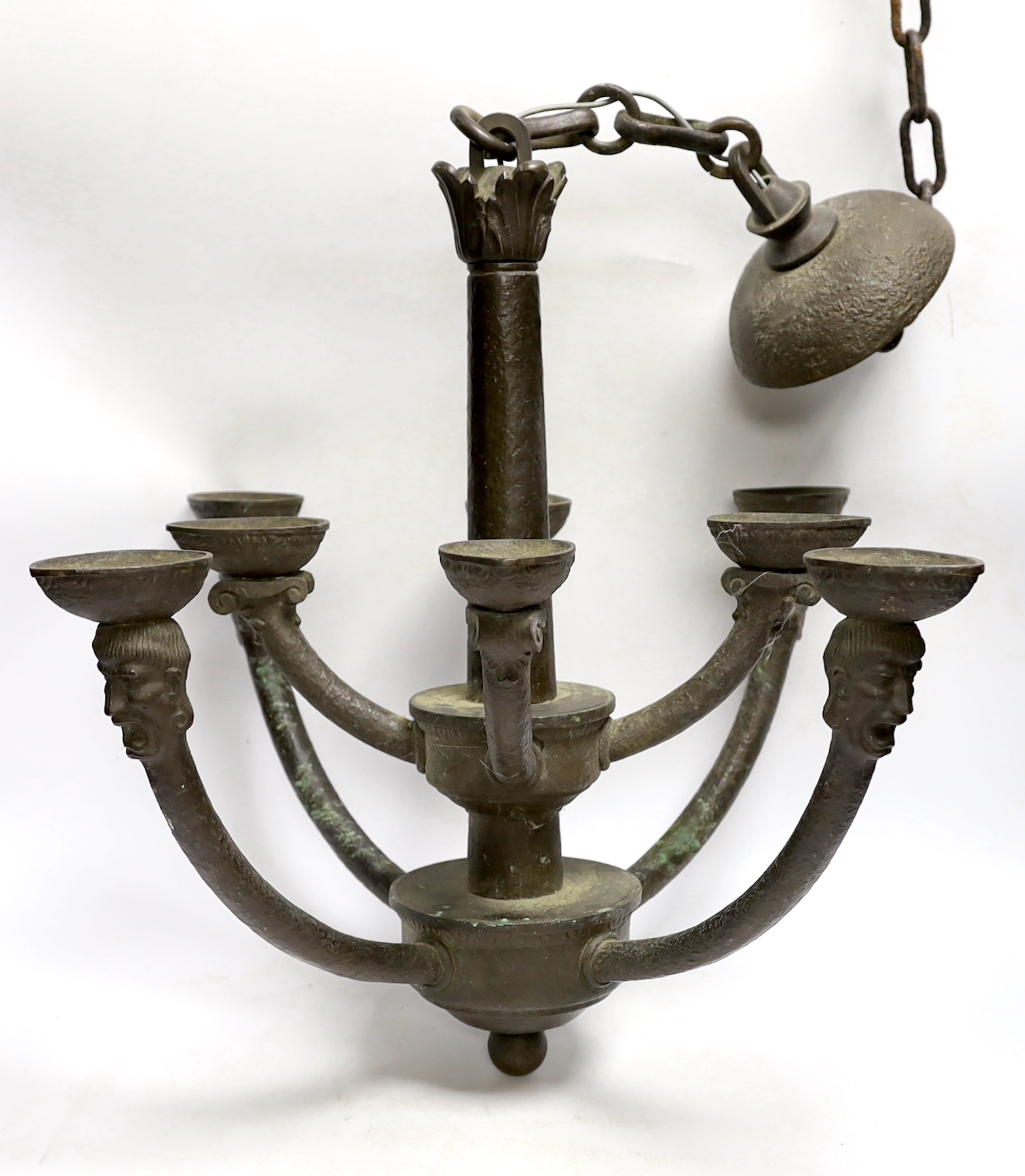 A bronze hanging ceiling light, with two tiers and eight face mask branches and large central chain, approx 47cm high not including chain